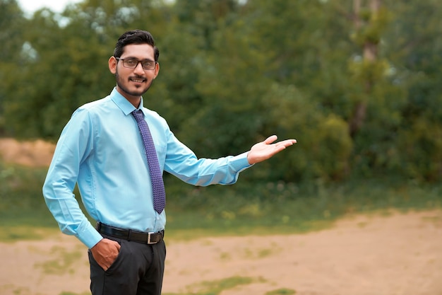 Young indian agronomist giving expresssion over nature background