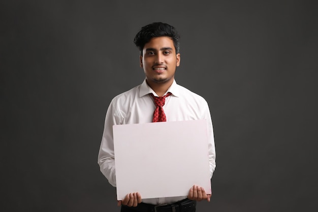 Young indian business man holding blank sign board.