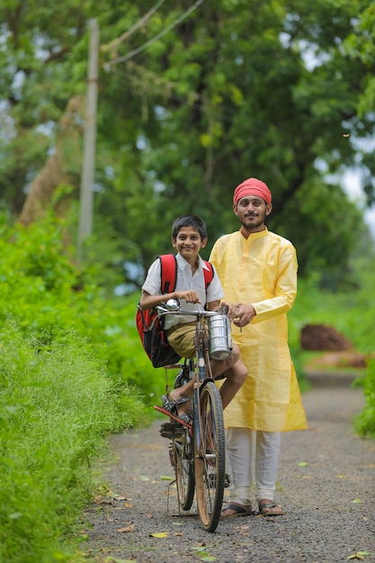 Young indian farmer and his son going to school on cycle