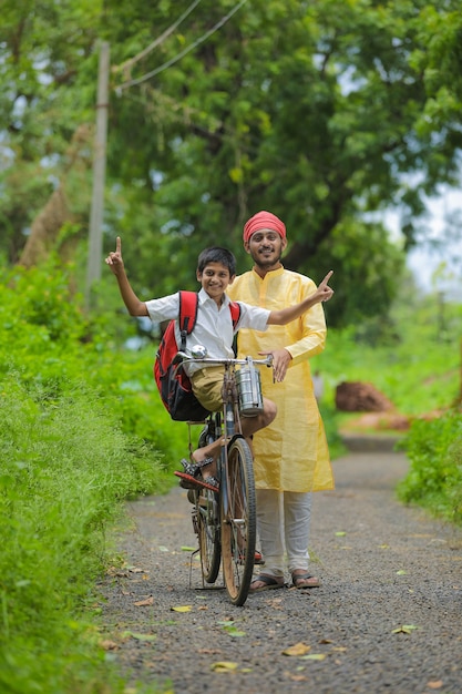 Young indian farmer and his son going to school on cycle