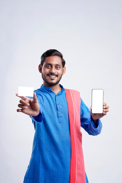 Young indian farmer showing card and smartphone on white background