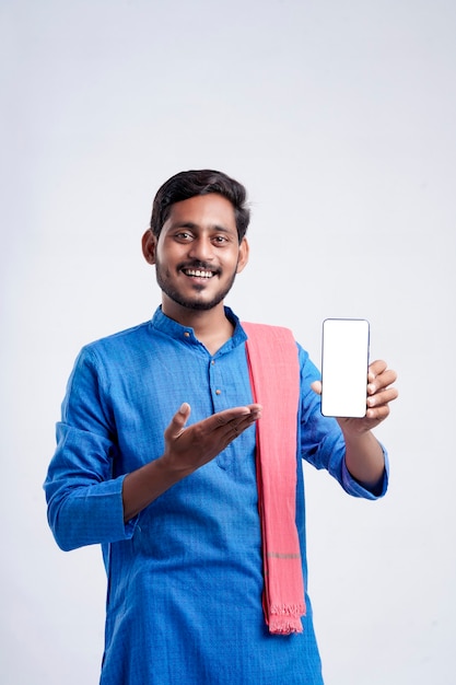 Young indian farmer showing smartphone and giving expression on white background.