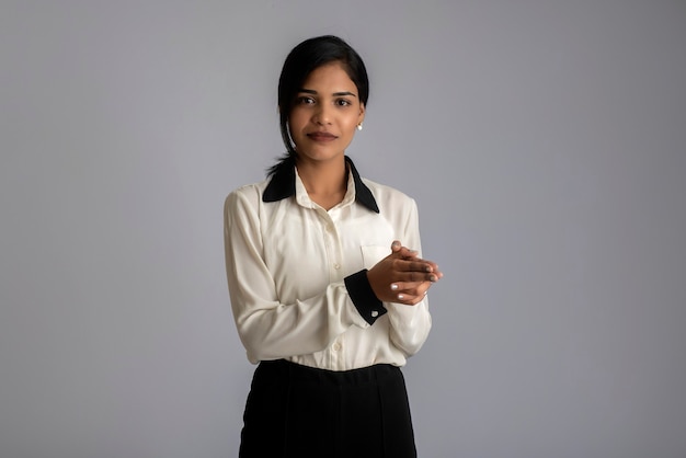 Young Indian girl using a mobile phone or smartphone on gray wall