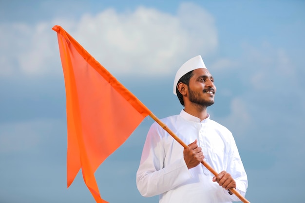 Young indian man (pilgrim) in traditional wear and waving religious flag.