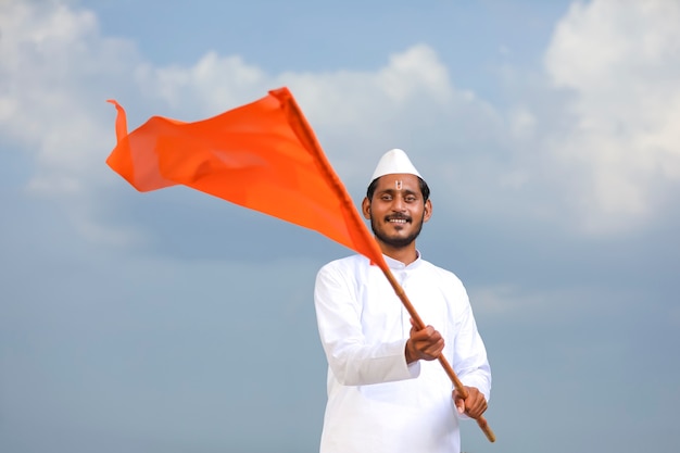 Young indian man (pilgrim) in traditional wear and waving religious flag.