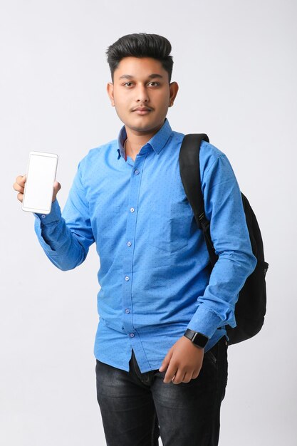 Young indian man showing smartphone screen on white background.