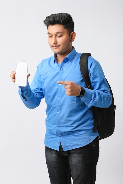 Young indian man showing smartphone screen on white background.