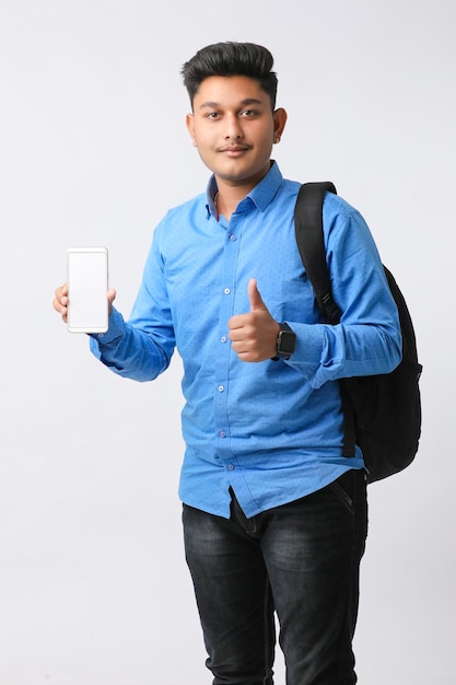 Young indian man showing smartphone screen on white background.