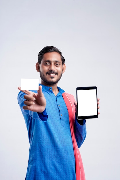 Young indian man showing tablet and card over white background.