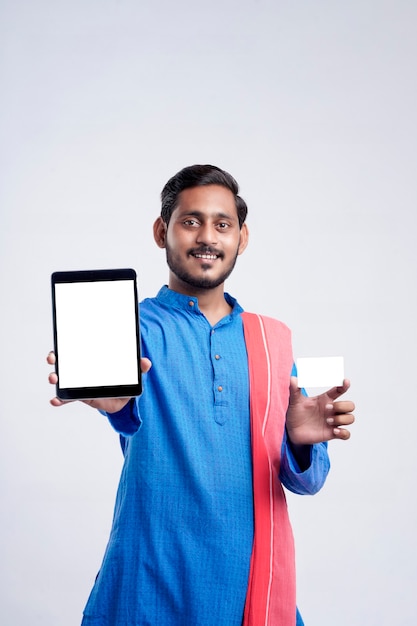 Young indian man showing tablet and card over white background.