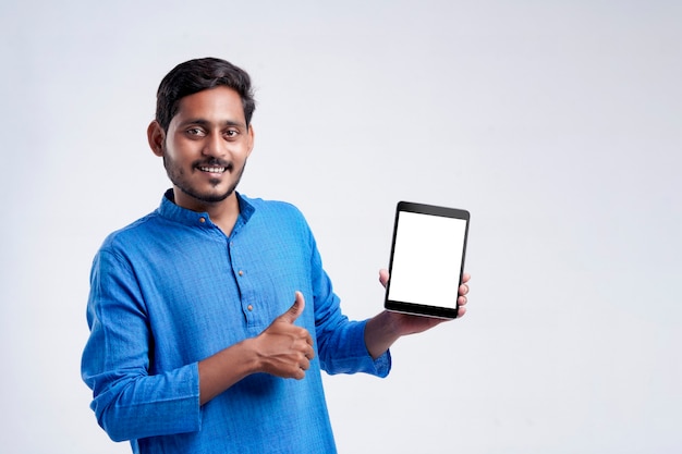 Young indian man showing tablet over white background.