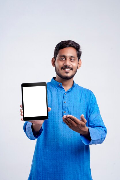 Young indian man showing tablet over white background.