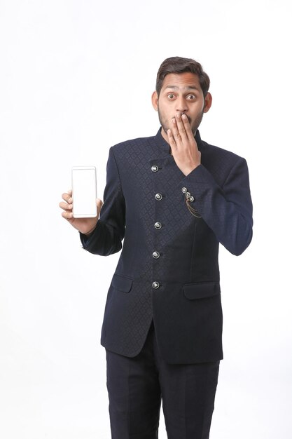 Young indian man in tradition wear and showing smartphone screen on white background.