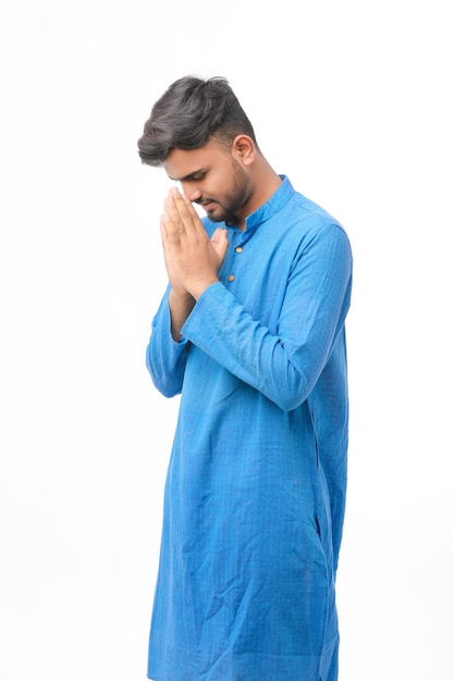 Young indian man in traditional wear and giving namaste or welcome gesture.