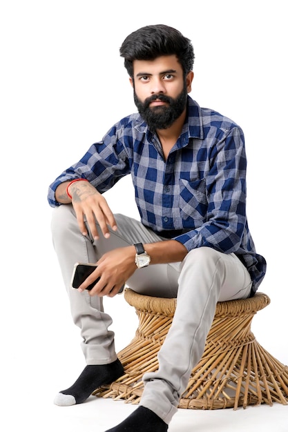 Young indian man using smartphone and giving expression on white background