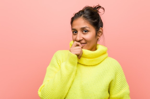 Young indian woman against a pink wall