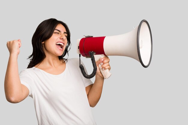 Young Indian woman holding a megaphone isolated