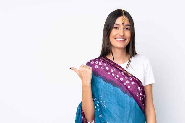 Young Indian woman isolated on white wall pointing to the side to present a product