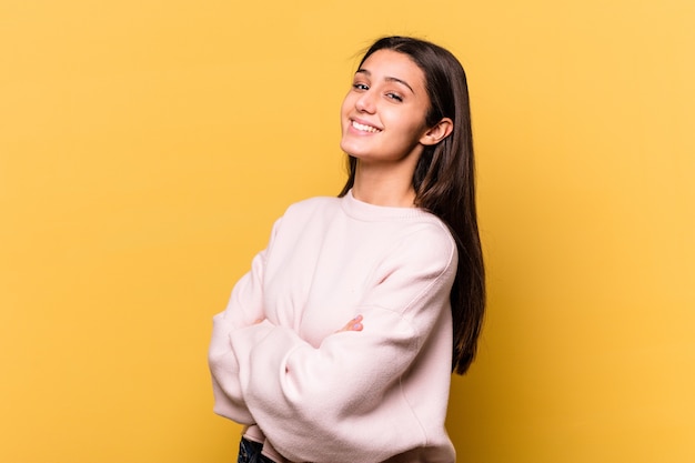 Young Indian woman isolated on yellow wall happy, smiling and cheerful.