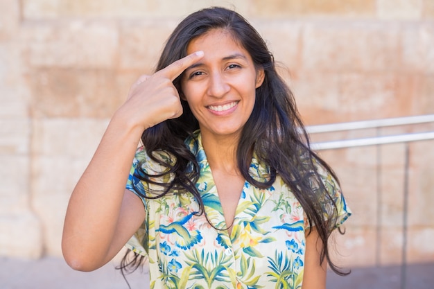 young indian woman pointing her forehead in the street