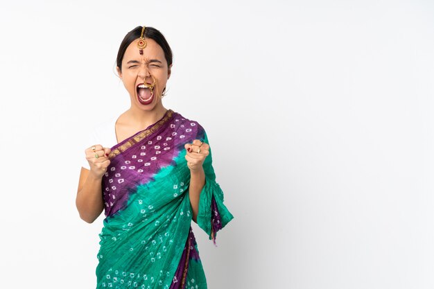 Young indian woman on white wall celebrating a victory in winner position