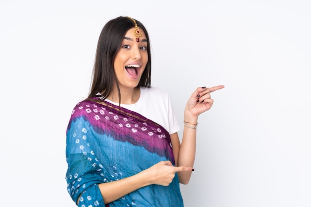 Young Indian woman on white wall surprised and pointing side