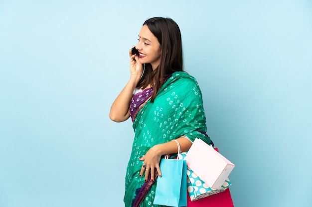 Young Indian woman with shopping bags keeping a conversation with the mobile phone with someone