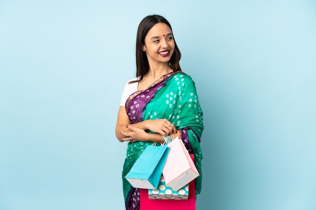 Young Indian woman with shopping bags looking to the side and smiling