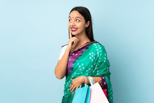 Young Indian woman with shopping bags thinking an idea while looking up