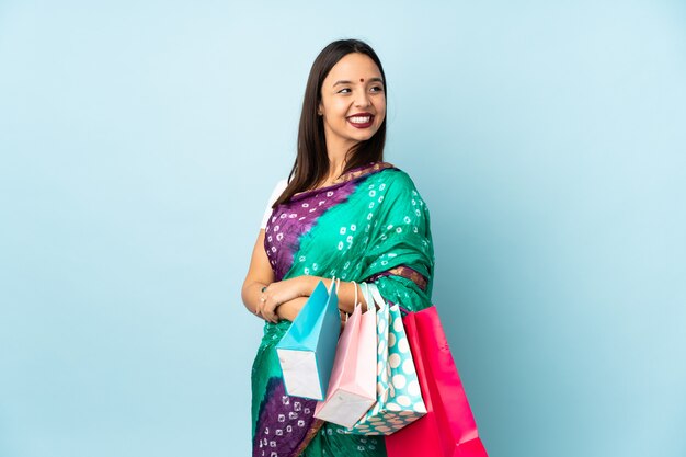 Young Indian woman with shopping bags with arms crossed and happy