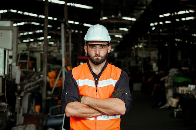 Young  industrial worker man working with metal machine in factory with many equipment