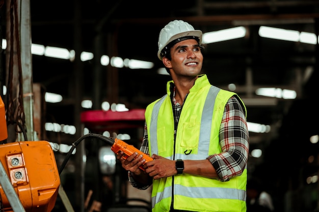 Young  industrial worker man working with metal machine in factory with many equipment