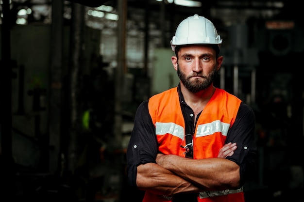 Young  industrial worker man working with metal machine in factory with many equipment