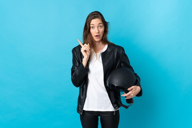 Young Ireland woman holding a motorcycle helmet isolated on blue background intending to realizes the solution while lifting a finger up