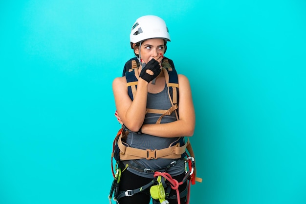 Young Italian rockclimber woman isolated on blue background surprised and shocked while looking right