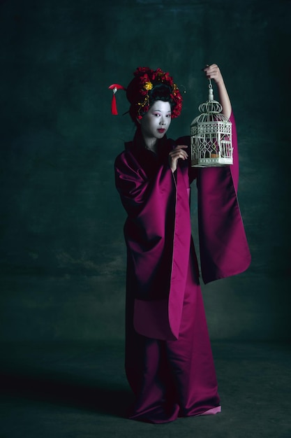 Young japanese woman as geisha on dark green