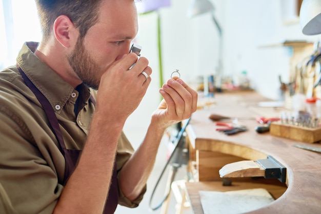 Young Jeweler Appraising Ring in Shop