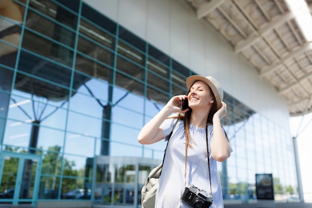 Young joyful traveler tourist woman with retro vintage photo camera talk on mobile phone call friend