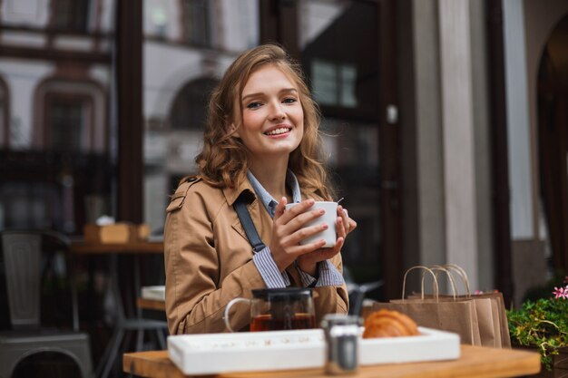 Young joyful woman in trench coat happily 