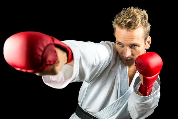 Young K1 fighter punching. Isolated over black background.