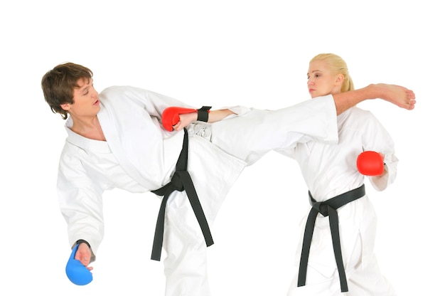 Young karateka students in white kimono black belts in combat gloves train to practice blows with kicking and hands on a white background