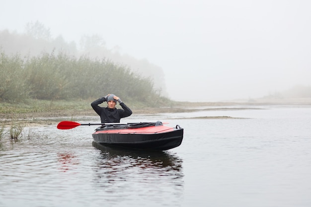 Young kayaker posing in his canoe and keeping hands on head