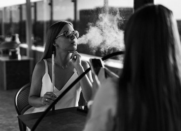 Young ladies relaxing with hookah Elegant girls in bar smoking