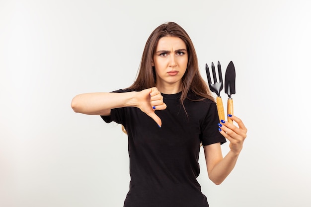 Young lady holding gardening tools and gesture thumb down