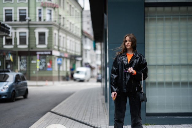 Young lady in leather jacket stand in urban city with credit card in hand