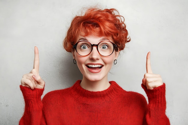 Young lady pointing up and right in wool cardigan and looking happy