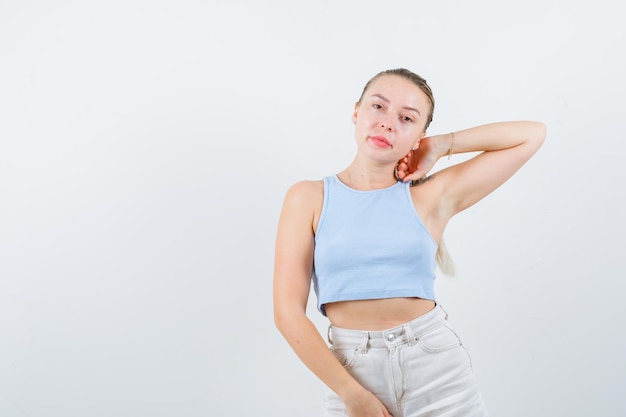 young lady puts her hand back of her neck on white background