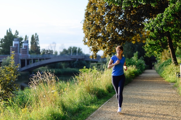 Photo young lady running on a rural road during sunset