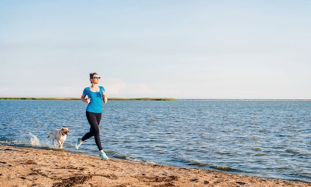 Young lady running. Woman runner running at the sunny summer sand beach. Workout near ocean sea coast. Beautiful fit girl. Fitness model caucasian ethnicity outdoors. Weight loss exercise. Jogging.