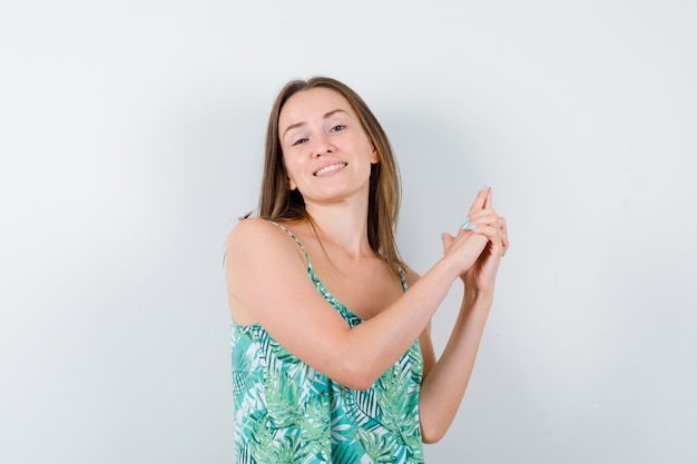 Young lady showing gun gesture in blouse and looking confident , front view.